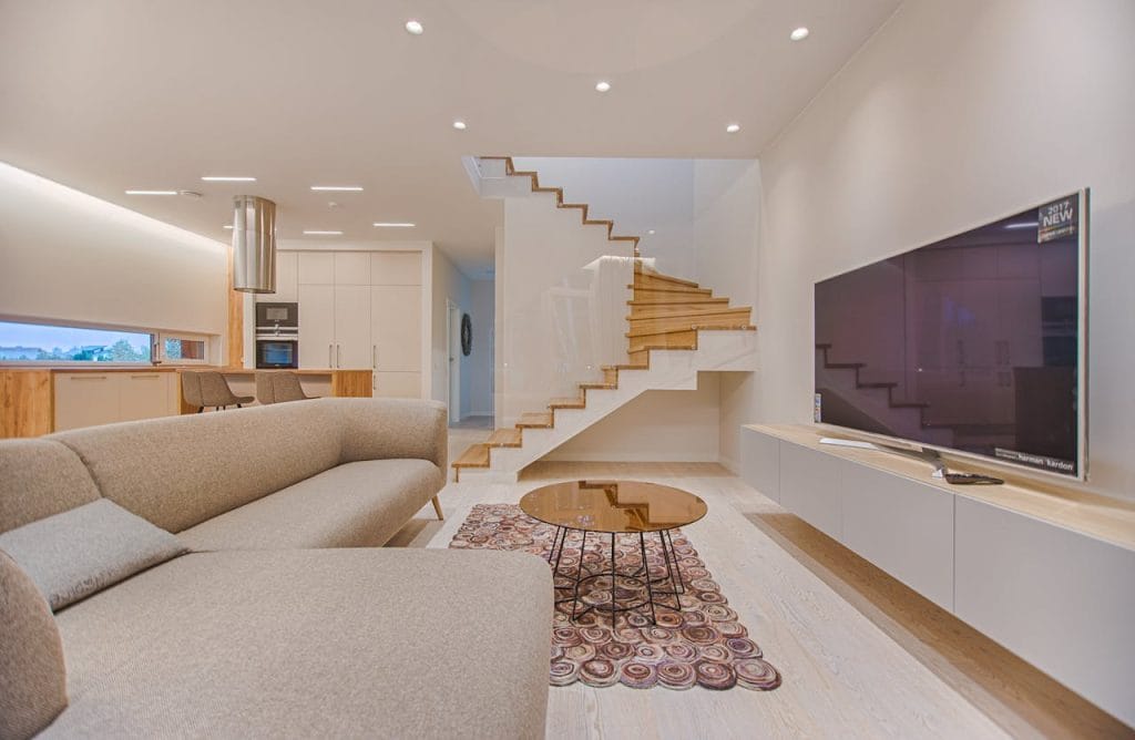Demo Post 3 1 Spacious modern living room featuring stairs, a TV, and sleek furniture design.